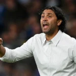 Marvin Compper geeft instructies langs de zijlijn in een wit hemd.