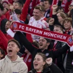 Jubelende supporters van Bayern München in het stadion met een Bayern-sjaal.