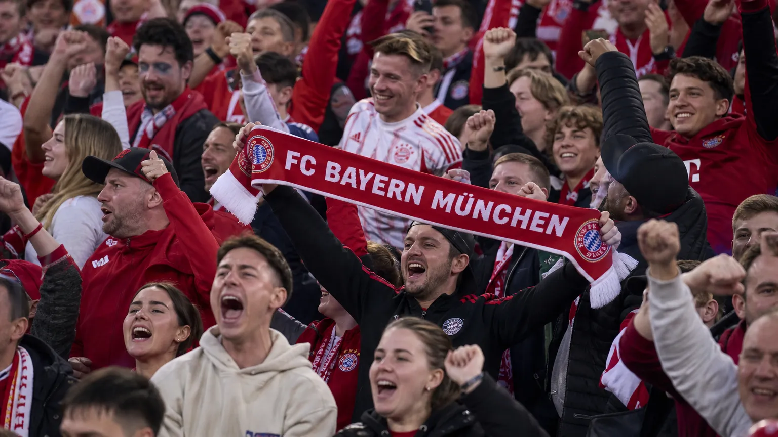 Jubelende supporters van Bayern München in het stadion met een Bayern-sjaal.