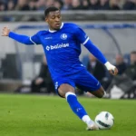 Een KAA Gent-speler in blauw wedstrijdtenue in duel om de bal.