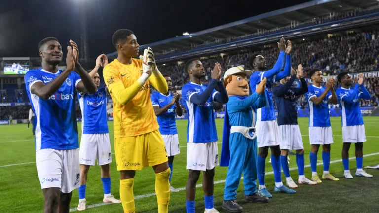 Een groep spelers van KRC Genk applaudisseert langs het veld voor de supporters.