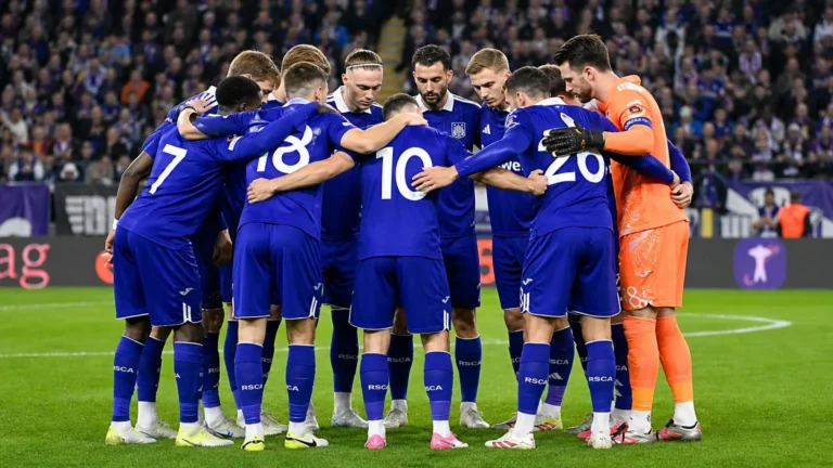 Een groep Anderlecht-spelers in paarse wedstrijdtenues verzamelt zich voor een match.