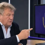 Jan Boskamp in een voetbalanalysestudio met een scherm waarop het embleem van Anderlecht zichtbaar is.