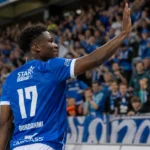 Rafiu Durosinmi van KRC Genk steekt zijn arm op naar de thuistribune.