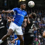Rafiu Durosinmi van Racing Genk in een luchtduel tijdens een voetbalwedstrijd.