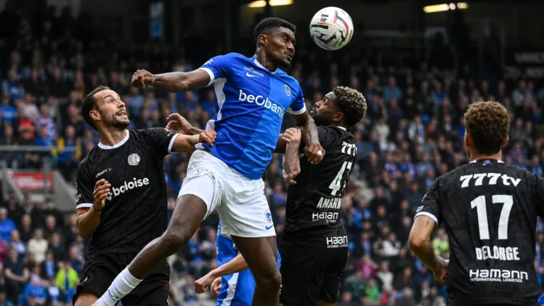 Rafiu Durosinmi van Racing Genk in een luchtduel tijdens een voetbalwedstrijd.