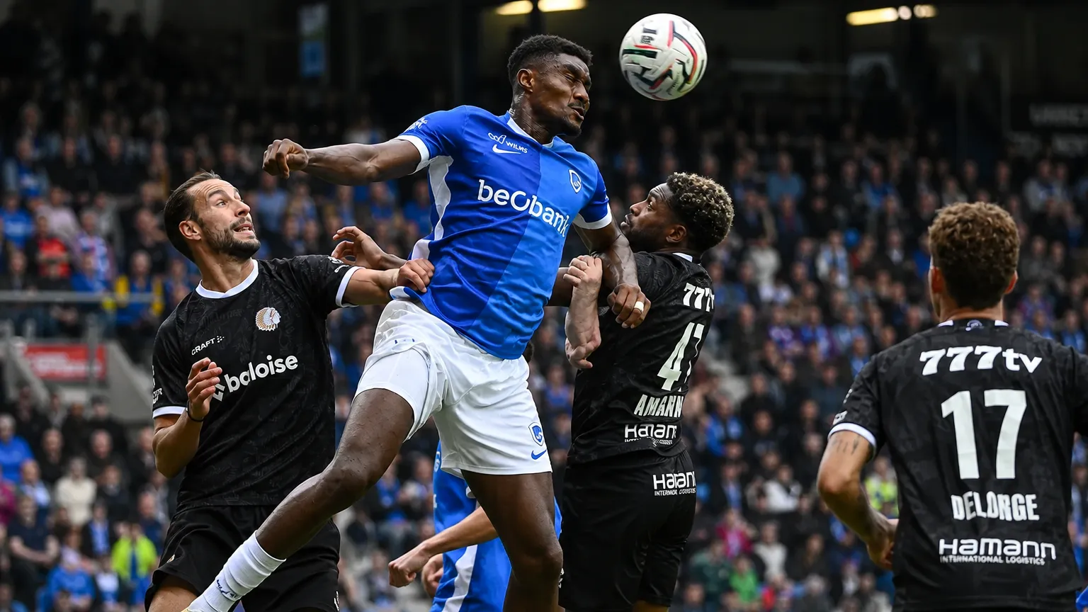 Rafiu Durosinmi van Racing Genk in een luchtduel tijdens een voetbalwedstrijd.