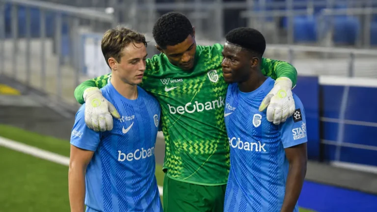Drie voetballers in blauwe en groene wedstrijdtenues op het veld.