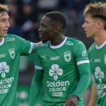 Drie spelers van RAAL La Louvière in groen tenue tijdens een korte onderbreking op het veld.