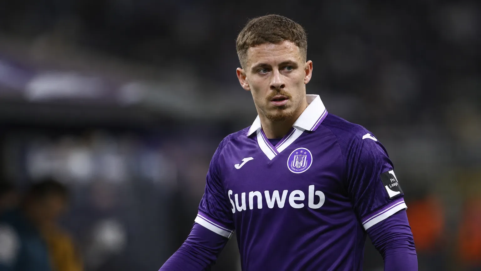 Thorgan Hazard in het paarse wedstrijdshirt van Anderlecht langs het veld tijdens een avondwedstrijd.