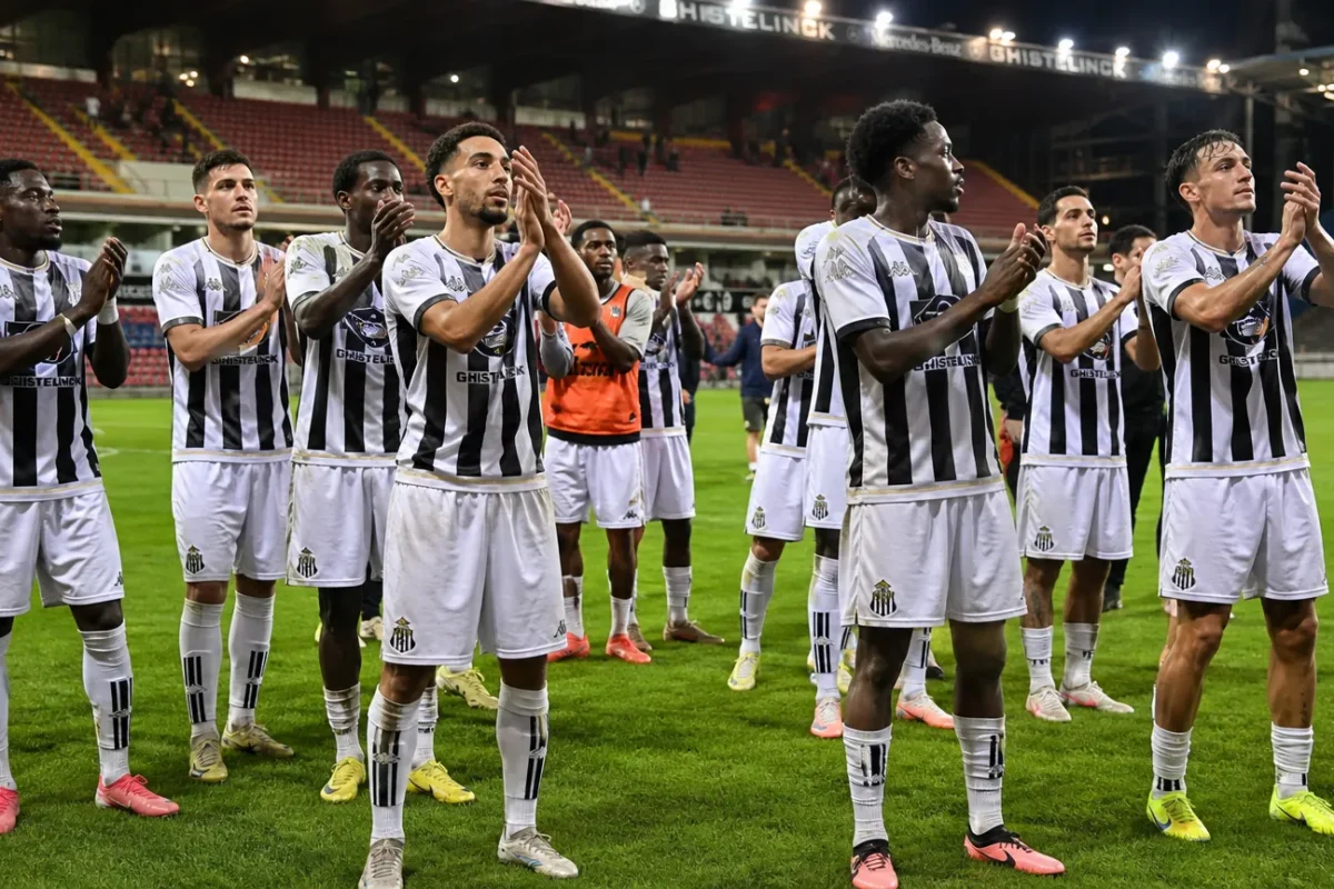 Spelers van Sporting Charleroi applaudisseren samen op het veld onder stadionlichten.