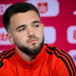 Nicolas Raskin tijdens een persmoment in een voetbalmediazaal.