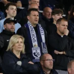 Een collectieve groep supporters van Sporting Hasselt in de tribune met een club-sjaal.