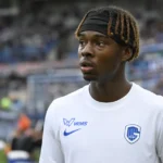 Een KRC Genk-speler in een wit shirt aan de rand van het veld.