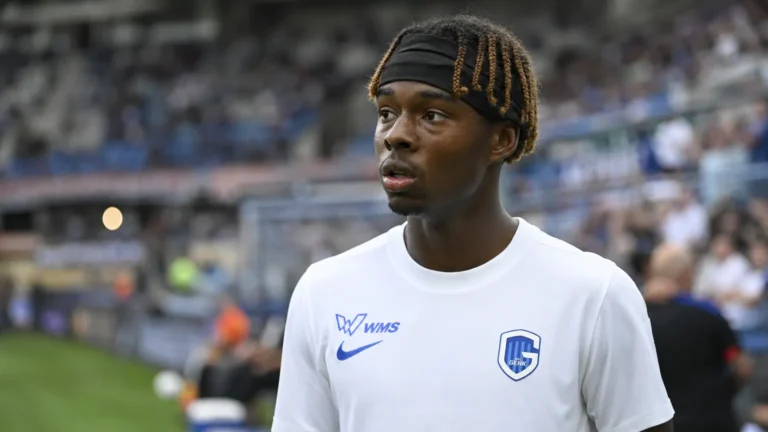 Een KRC Genk-speler in een wit shirt aan de rand van het veld.