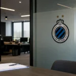 Een operationele kantoorruimte van Club Brugge met een discreet clubembleem aan een glazen wand.