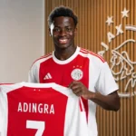 Simon Adingra poseert tijdens een officiële Ajax-shirtpresentatie.