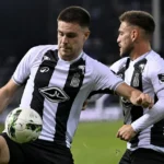 Twee spelers in zwart-witte shirts tijdens een wedstrijdmoment op het veld.