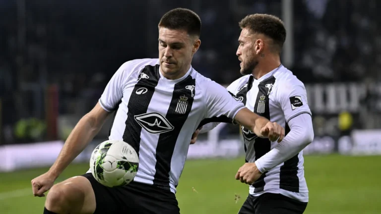 Twee spelers in zwart-witte shirts tijdens een wedstrijdmoment op het veld.