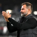 Een coach van Club Brugge applaudisseert langs de zijlijn in een stadion.
