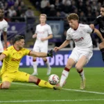 Spelers en een doelman in actie voor het doel tijdens een Belgische competitiewedstrijd.