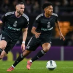 Twee Anderlecht-spelers in donkere wedstrijdshirts tijdens een wedstrijdactie.
