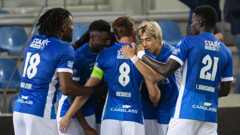 Een groep voetballers in blauwe shirts viert samen tijdens een wedstrijdmoment.