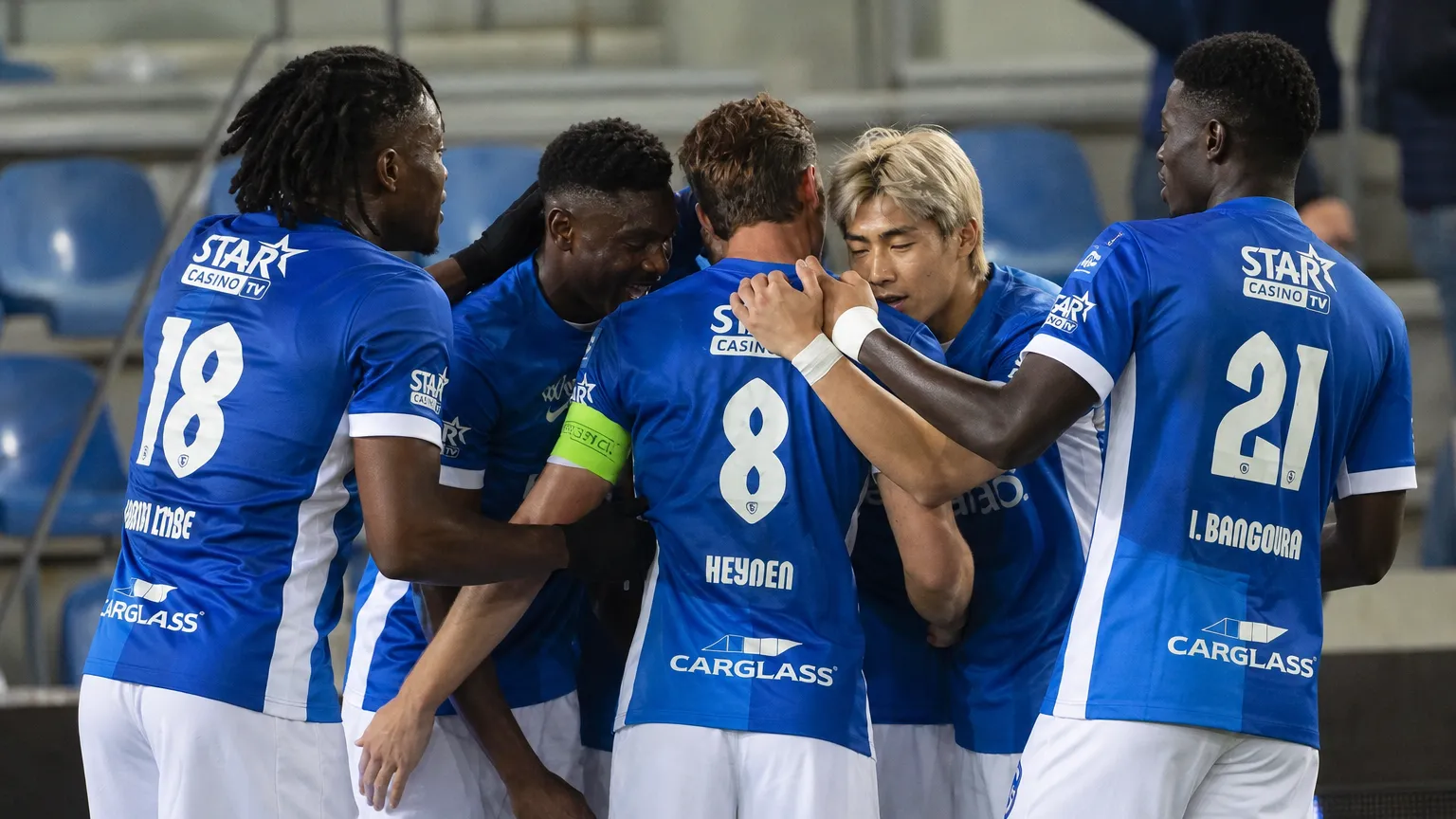 Een groep voetballers in blauwe shirts viert samen tijdens een wedstrijdmoment.