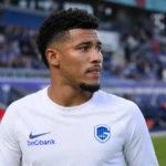 Kevin Amaro in een wit KRC Genk-tenue langs het veld.