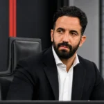Rúben Amorim in zwart pak tijdens een persconferentie van AC Milan.