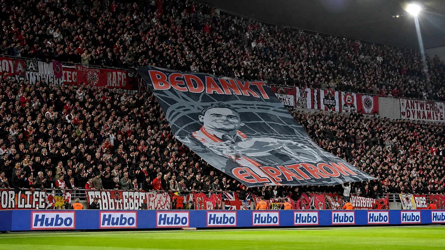 Een volle Antwerpse tribune met rood-witte supporters en een grote tifo op de Bosuil.