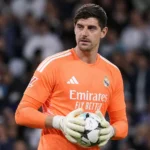 Thibaut Courtois in het oranje doelmanstenue van Real Madrid tijdens een wedstrijdmoment.