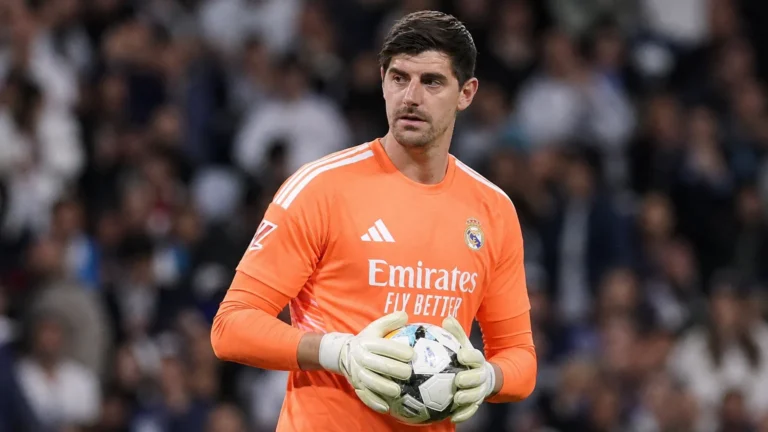 Thibaut Courtois in het oranje doelmanstenue van Real Madrid tijdens een wedstrijdmoment.