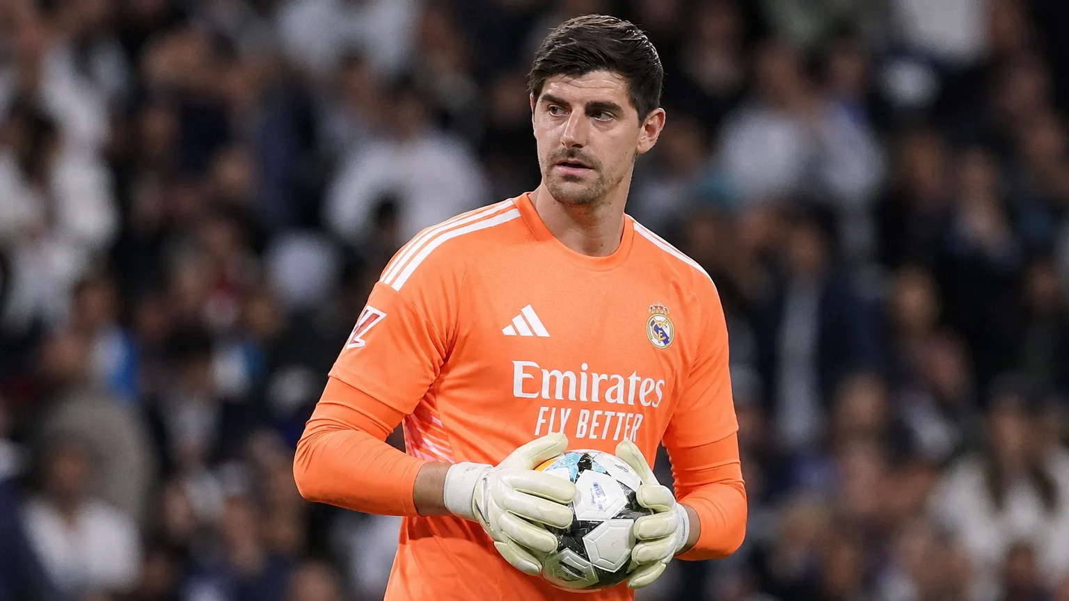 Thibaut Courtois in het oranje doelmanstenue van Real Madrid tijdens een wedstrijdmoment.
