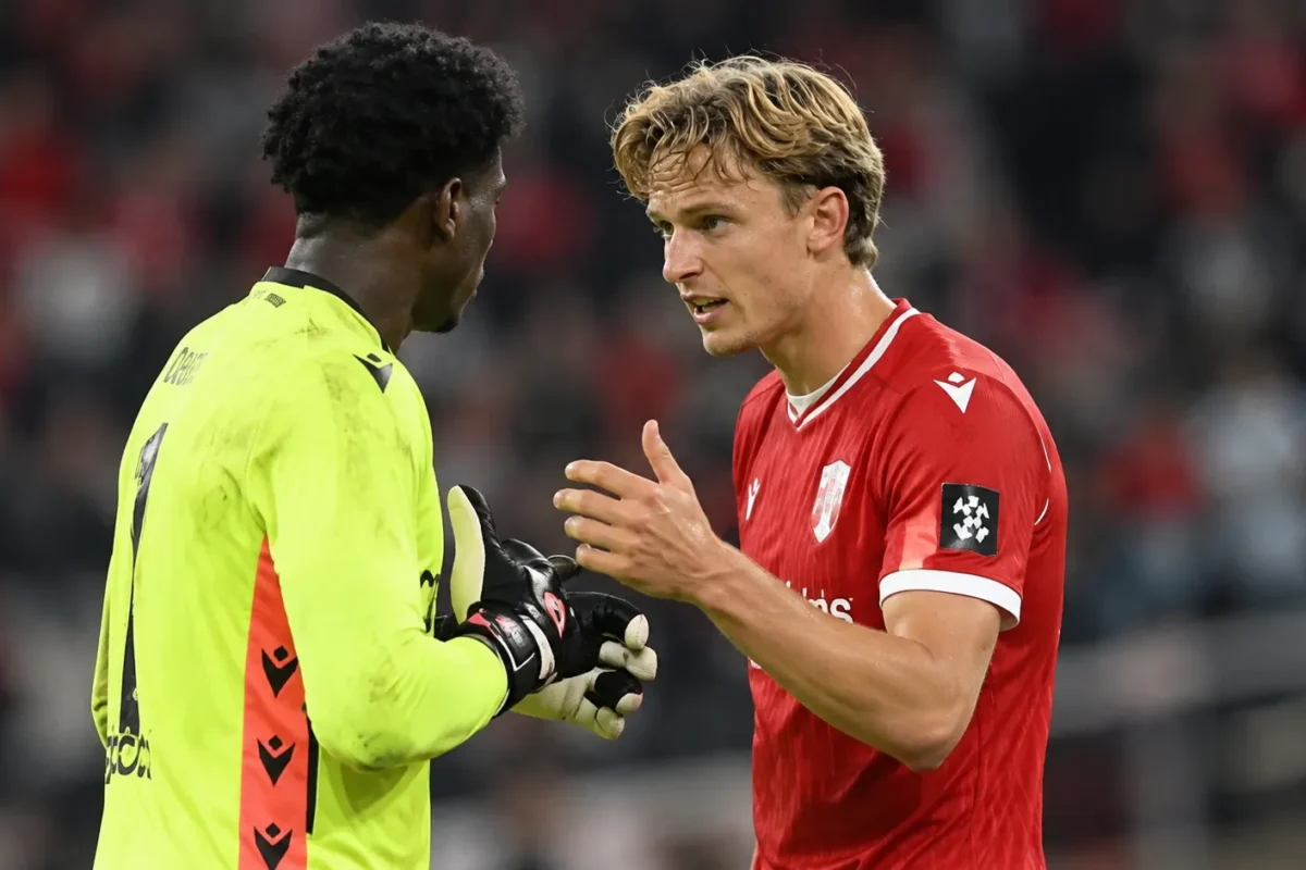Ibe Hautekiet in het rode Standard-shirt in gesprek met een doelman op het veld.