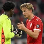 Ibe Hautekiet in het rode Standard-shirt in gesprek met een doelman op het veld.