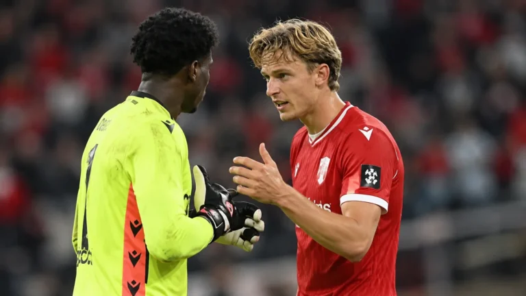 Ibe Hautekiet in het rode Standard-shirt in gesprek met een doelman op het veld.