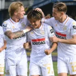 Een groep spelers van KVC Westerlo viert samen een doelpunt tijdens een wedstrijd.