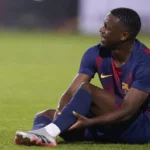 Jesse Bisiwu zit op het gras na een blessure tijdens een voetbalwedstrijd.