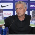 José Mourinho houdt tijdens een persconferentie twee uitgeprinte wedstrijdfoto's omhoog.
