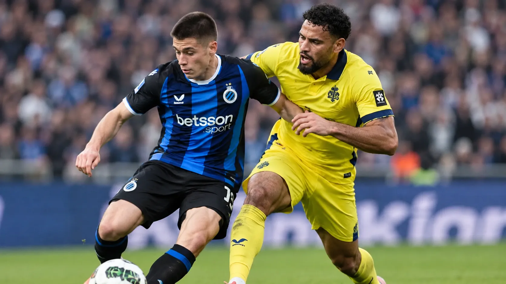 Twee voetballers in blauw-zwart en geel vechten een duel uit op het veld.