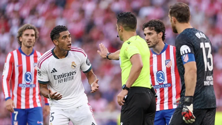 Scheidsrechter toont een kaart tijdens een derbyfase met spelers van Real Madrid en Atlético Madrid.