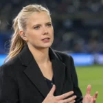 Noa Vahle tijdens een voetbaluitzending met een oortje en donkere blazer.
