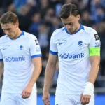 Twee spelers in witte shirts lopen na afloop over het veld.