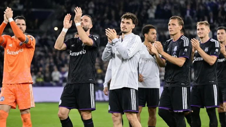 Een groep Anderlecht-spelers applaudisseert na een competitiematch op het veld.