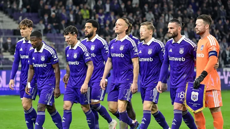 Spelers van RSC Anderlecht wandelen samen op het veld na een wedstrijd.