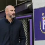 Een clubvertegenwoordiger van Anderlecht kijkt geconcentreerd rond in een stadionomgeving.