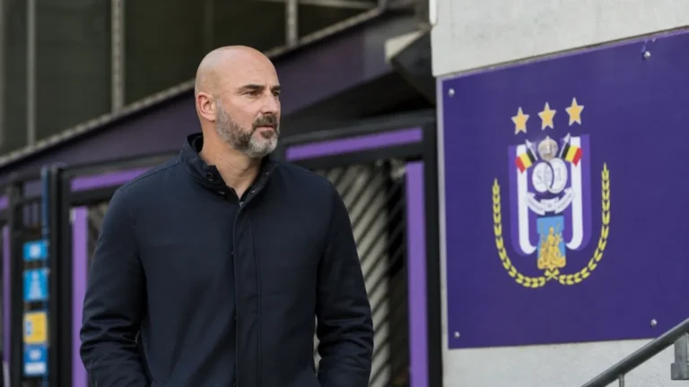 Een clubvertegenwoordiger van Anderlecht kijkt geconcentreerd rond in een stadionomgeving.