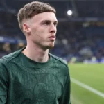 Cole Palmer in een groen Chelsea-warm-upshirt naast het veld.