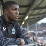 Joel Ordóñez in een Club Brugge-trainingsjas aan de rand van een stadiontribune.